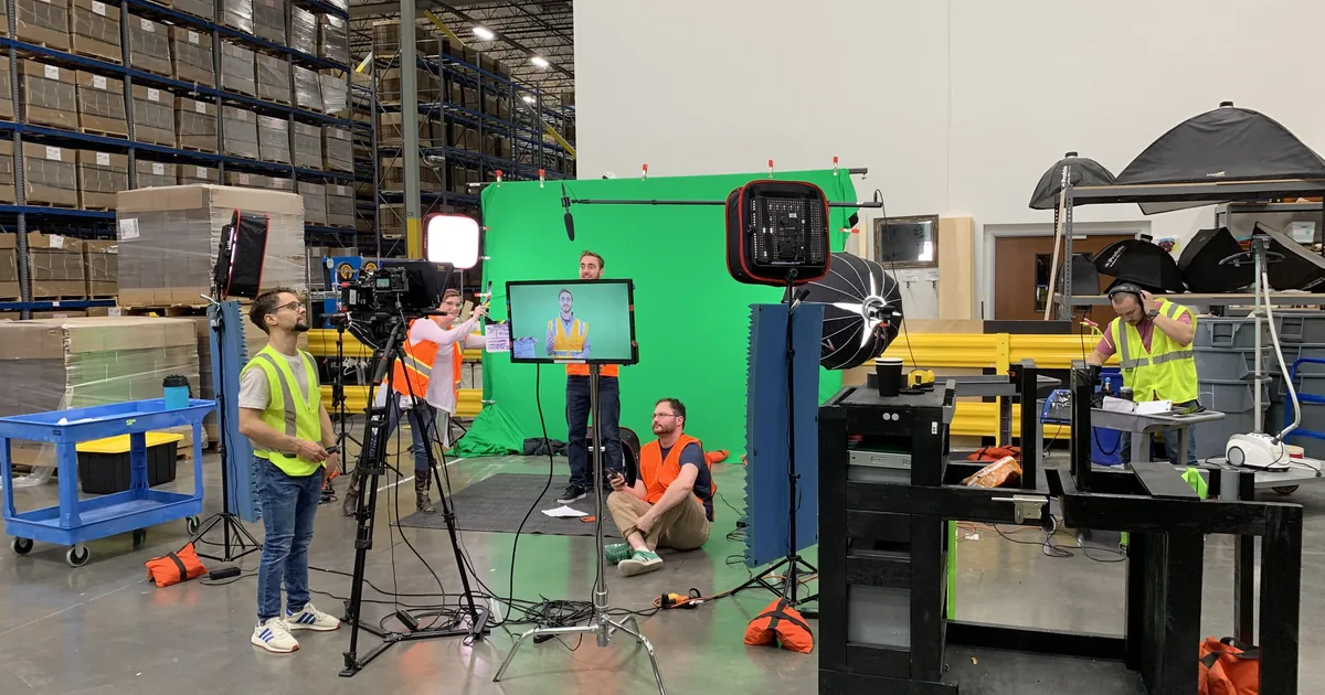 Green screen and lighting rigged inside a Chewy fulfillment warehouse for a training video shoot