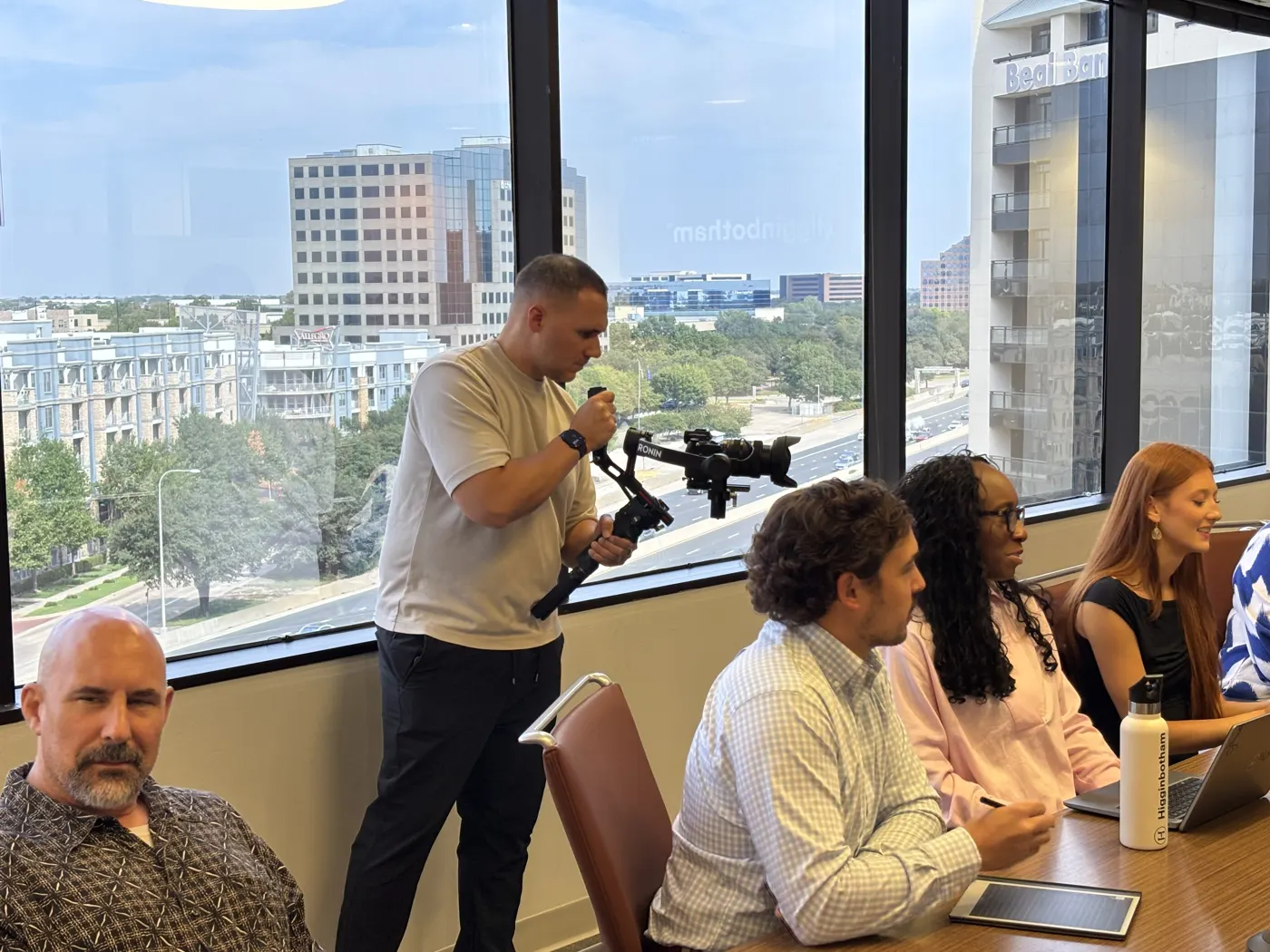 Camera operator with a stabilizer filming a team meeting around a conference table
