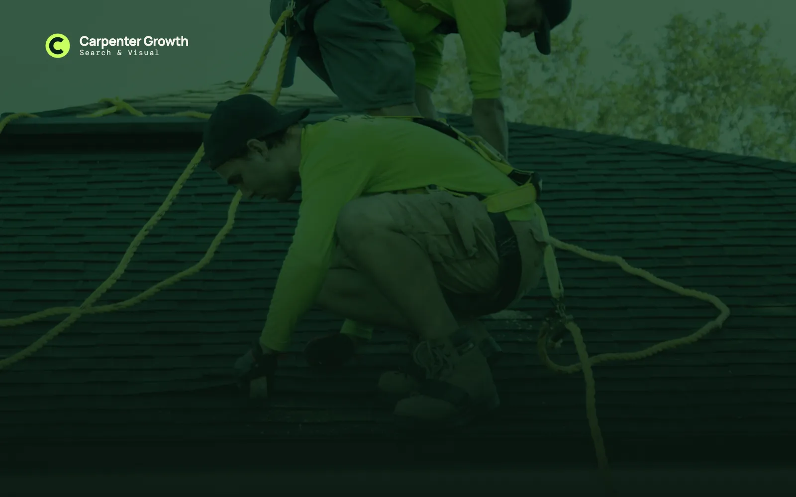 Roofers in safety harnesses working on a shingle roof